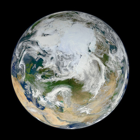 A photo of the northern portion of the Earth. Swirls of white cover it.