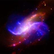M106: This image of galaxy M106 combines several kinds of light. Two of the arms (purple and blue) don't even show up in ordinary light, but are revealed in radio waves and X-rays.